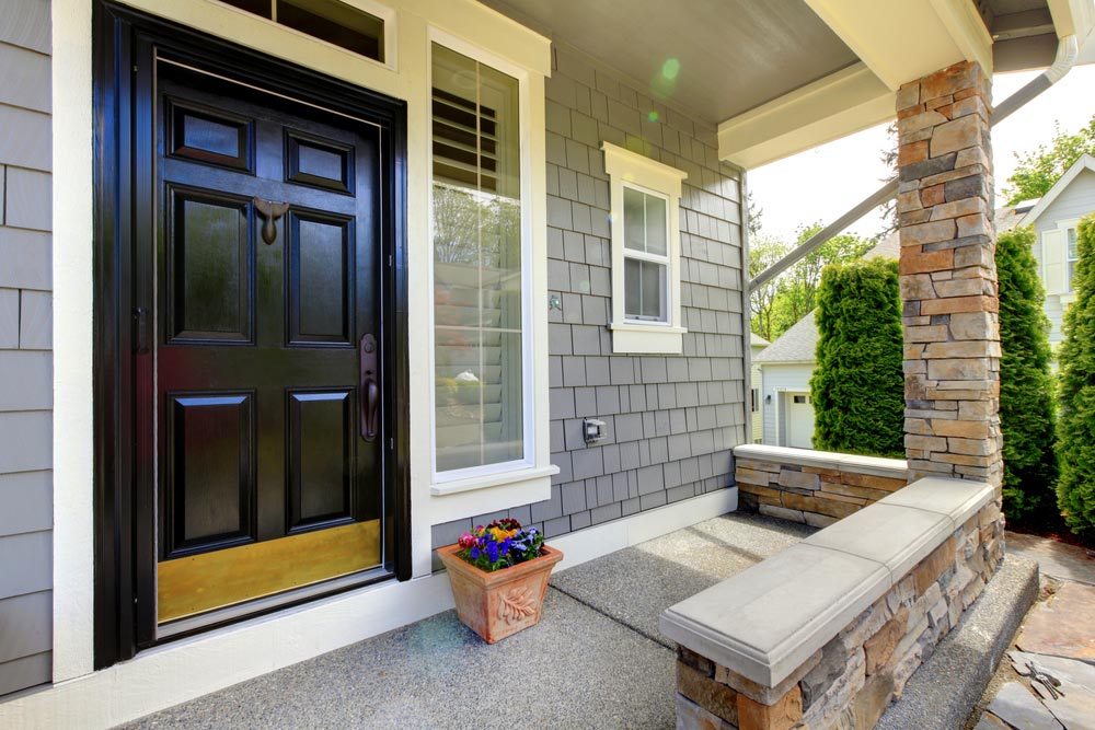 A front porch with a bench and potted plants.